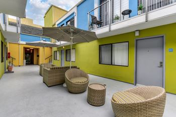 Community outdoor courtyard lounge area with wicker chairs and sun umbrellas.